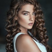 Hier zu sehen ist eine Frau mit gelockten Haaren und helleren Strähnen in braunem Haar | Trend Haarfarben 2020 - Hair&Style Altbach