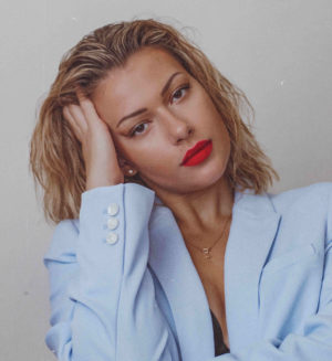 Hier zu sehen ist eine Frau in einem Blazer, die Sleek Back Hair als Frisur für fettige Haare trägt | Tipps gegen fettige Haare - Hair&Style Altbach